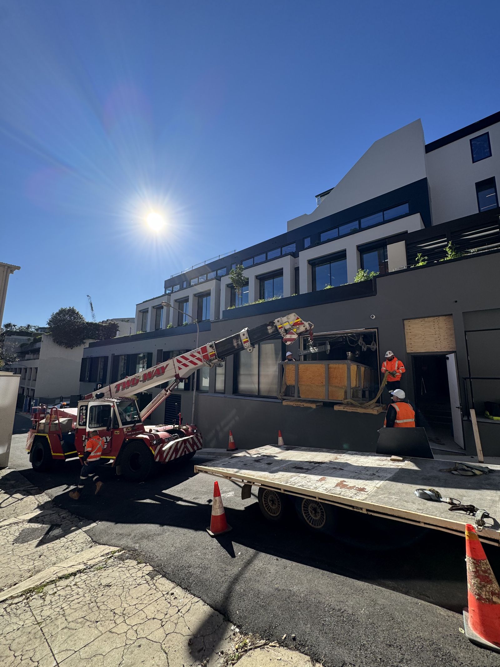 Crane lifting a composite plunge shell through a first-floor window opening at a Double Bay build