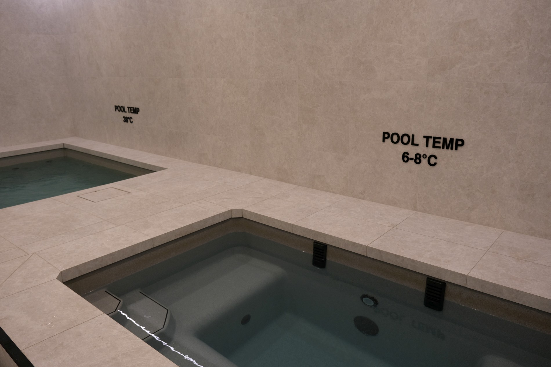 Commercial hot and cold immersion pools with temperature signage at a gym recovery zone